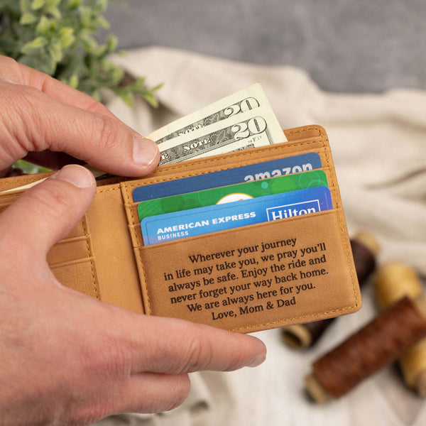 Hands holding an open light brown mens bifold retrieving cash bills - personalized graduation engraving on inside pocket
